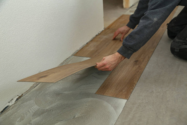 The worker installing the new vinyl tiles on the floor in the house - Fotó, kép