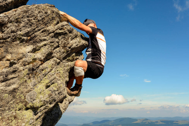 Ορειβασία στα Καρπάθια, ένας άνθρωπος σκαρφαλώνει σε μια βραχώδη κορυφή χωρίς προστασία, μόνος, ερασιτέχνης ορειβάτης. - Φωτογραφία, εικόνα