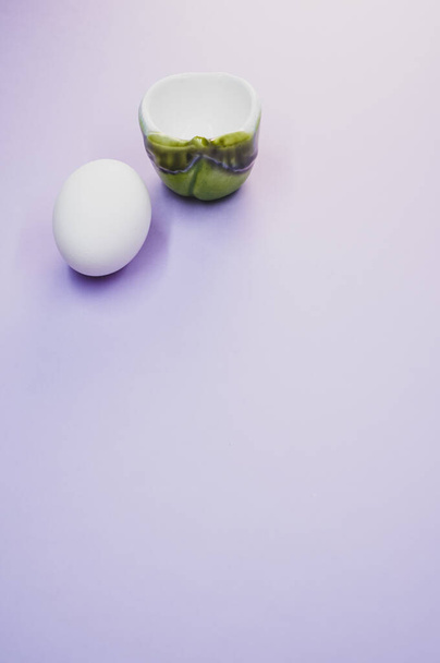 A vertical shot of a white egg and a cup - Fotoğraf, Görsel