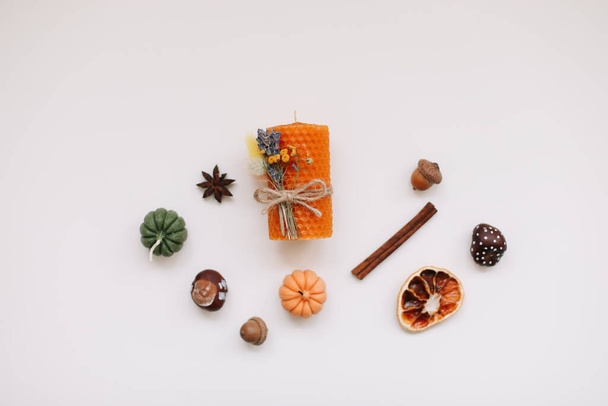 Autumn still life: candles, pumpkin, cinnamon, chestnuts, acorns on white background. Hygge lifestyle, cozy home decor. - Photo, image