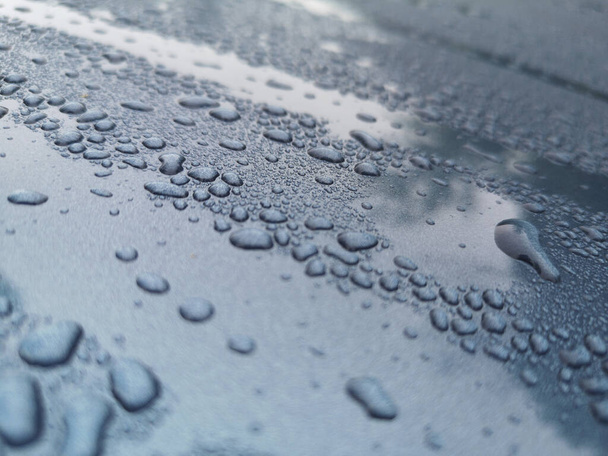 Un tiro selectivo del foco de las gotas de agua uno un capó azul del coche - Foto, Imagen