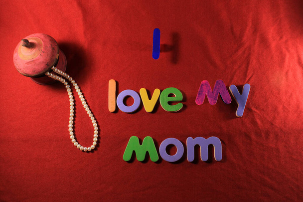 Lettres colorées avec J'aime ma mère isolée sur fond de tissu rouge. Je t'aime maman orthographiée avec des lettres colorées et coeur rouge pour la fête des mères. Boîte cadeau fête des mères. - Photo, image