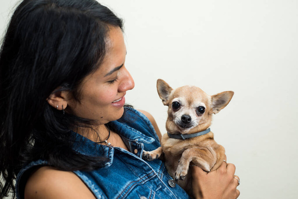 A Latin woman holding her brown chihuahua - Foto, Bild