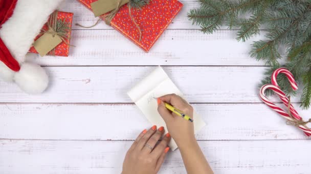 Flat lay of female hand writing 2021 to do list, Χριστουγεννιάτικη διακόσμηση γύρω, ξύλινο φόντο. Έννοια του νέου έτους, σχέδια για το έτος. - Πλάνα, βίντεο