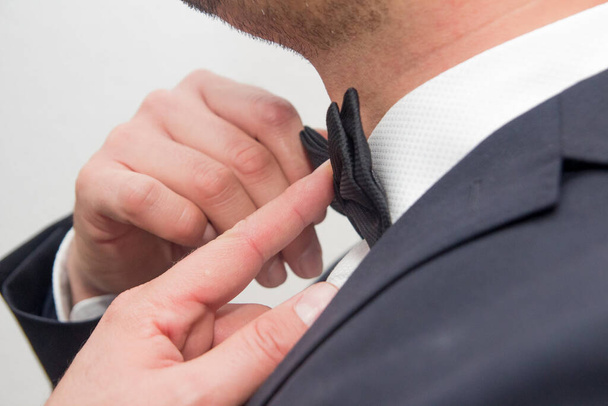 A closeup shot of a male in a suit fixing his bow - Foto, immagini