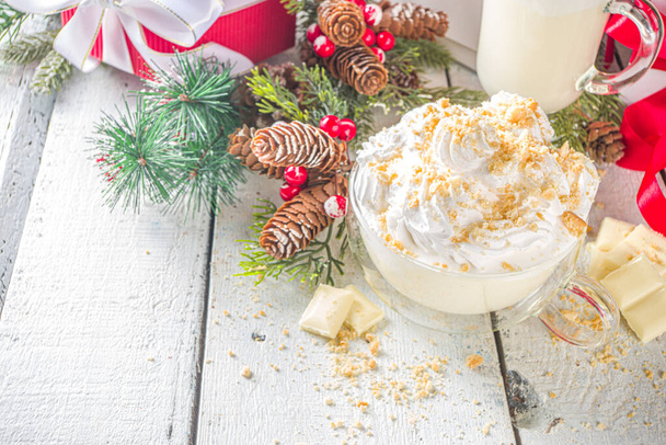Christmas winter hot chocolates idea, recipe. Cheesecake hot chocolate with cheesecake aroma and crumbs, white chocolate and creamy milk. On white wooden table background with Christmas decor - Photo, Image
