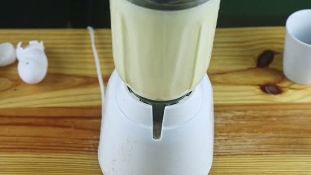 top view closeup ηλεκτρικό μπλέντερ γυάλινο δισκοπότηρο ανάμειξη γάλα, συμπυκνωμένο γάλα, και τα αυγά - Πλάνα, βίντεο