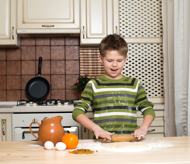 Little boy in the kitchen preparing the dough using rolling. - Photo, image