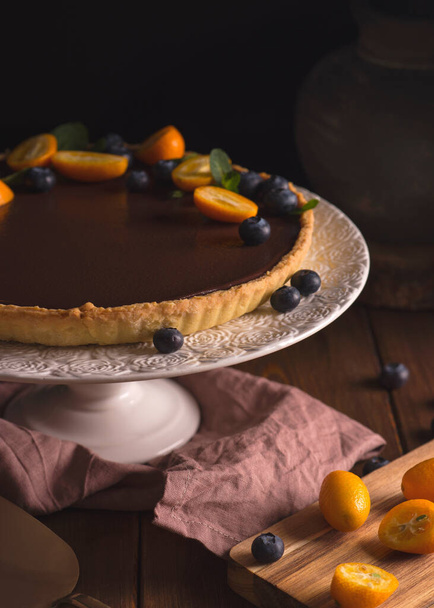 Chocolate tart on a dark background. Decorated with berries. Place for text - Foto, Bild
