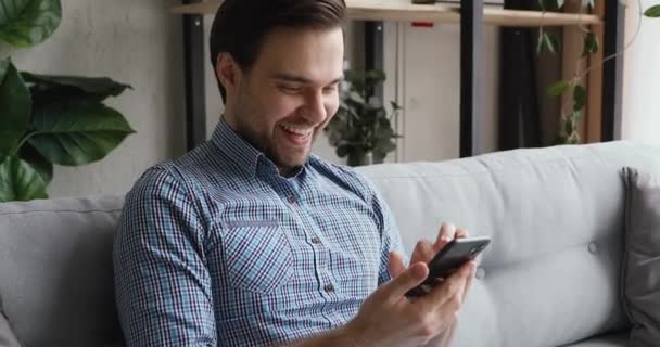 Joyful young caucasian man laughing at funny photo content. - Video, Çekim