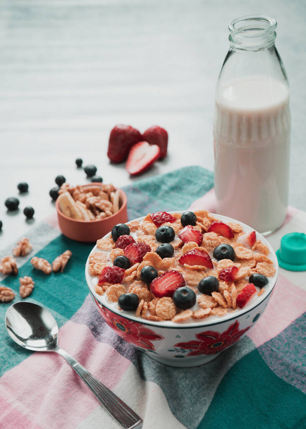 A selective focus shot of a bowl with delicious cereals with milk and berries - 写真・画像