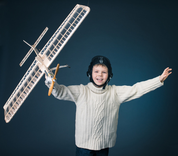 Happy boy playing with a wooden plane model - Zdjęcie, obraz