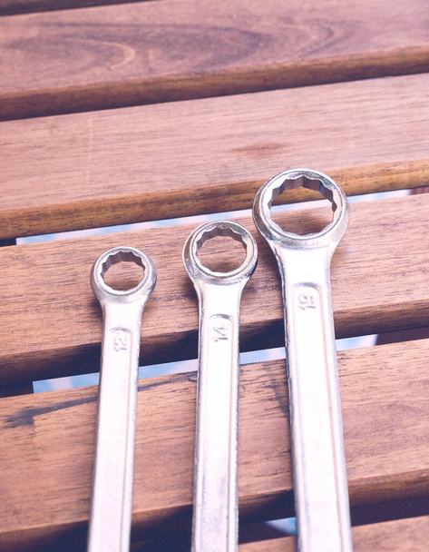 A vertical shot of three different wrenches on a wooden surface - Foto, afbeelding