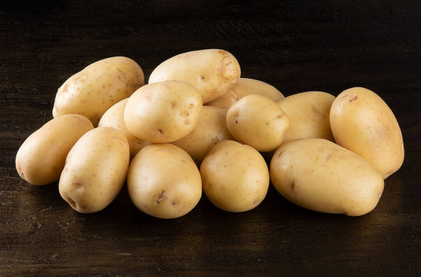 Pile of potatoes lying on rustic background. - Foto, Imagen