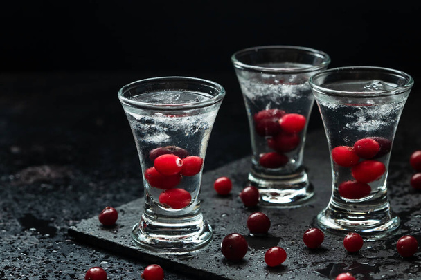 Cold Russian vodka with ice and  cranberry on  dark  stone table , selective focus with  shallow depth of field - Valokuva, kuva