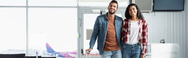 ευτυχισμένο πολυπολιτισμικό ζευγάρι με τα πόδια στο αεροδρόμιο, πανό - Φωτογραφία, εικόνα