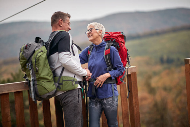 An elderly couple in love enjoying lovely moments on the top of a watchtower in the forest on a beautiful autumn day - Valokuva, kuva