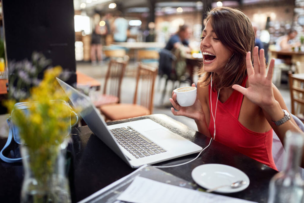 young beautiful girl  enjoying coffee and chat with friend on the laptop - Фото, изображение