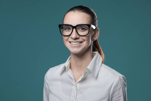 Young confident businesswoman posing with glasses, she is smiling at camera - Foto, afbeelding