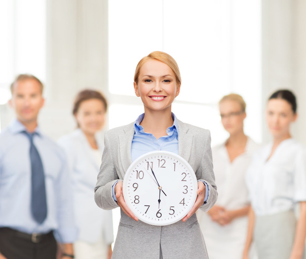 Smiling businesswoman with wall clock - Foto, Imagen