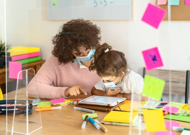Maestra con niños usando mascarilla facial en el aula preescolar durante la pandemia del virus corona - Concepto de salud y educación - Foto, imagen