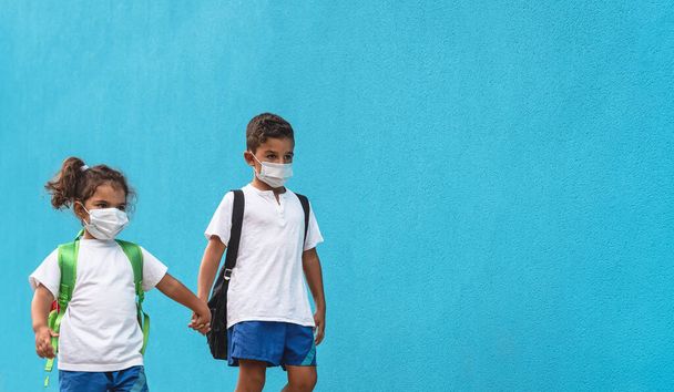 Dzieci noszące maskę ochronną na twarz powracające do szkoły podczas pandemii wirusa korony - koncepcja opieki zdrowotnej i edukacji - Zdjęcie, obraz