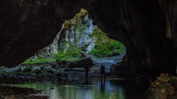 Dva lidé jásají nad jeskyní a je tam také řeka. Příroda venku je nádherná. - Záběry, video