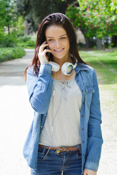 smiling beautiful young woman with earphones and calling someone - Foto, Imagen