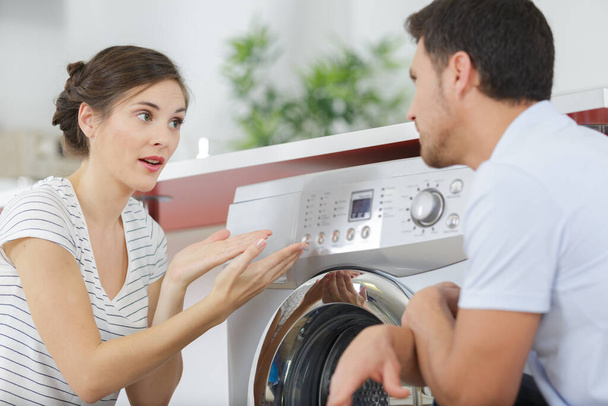 couple talking next to washing machine - Foto, imagen
