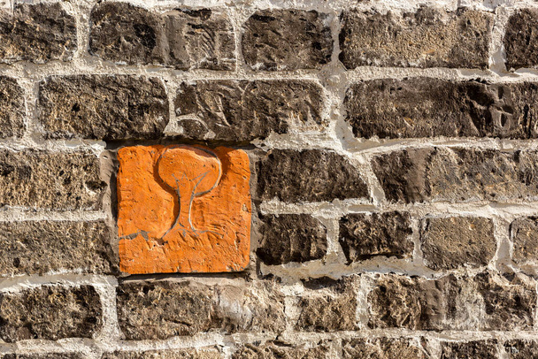 1つのオレンジレンガ、石の石積みの一部と灰色の古い石の壁の背景の断片 - 写真・画像