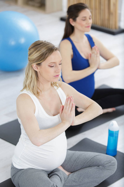 two pregnant women are relaxing during yoga class - Foto, Imagem