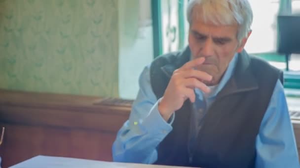 Deze oudere man zit rustig op een bankje en luistert naar drie oudere dames en hun gezang.. - Video