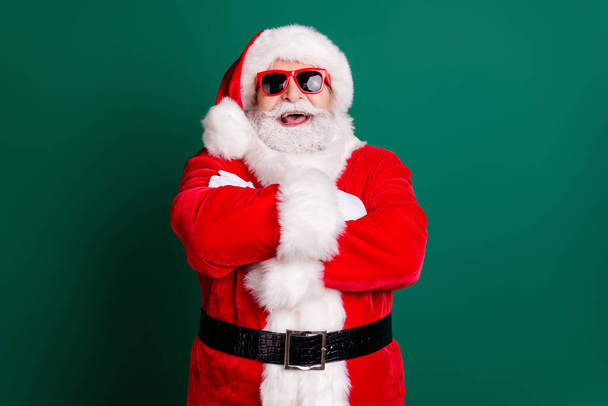 Photo of retired grandpa grey beard crossed arms confident laugh watch children play snowballs wear red santa costume x-mas coat gloves belt sunglass headwear isolated green color background - Foto, Imagen