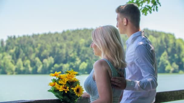 Una giovane coppia si sta godendo la splendida vista sul lago quando un uomo improvvisamente mette il braccio intorno alla schiena della sua donna e una spalla. - Filmati, video