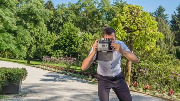 Ένας φωτογράφος είναι συγκεντρωμένος όταν φωτογραφίζει ένα ζευγάρι που παντρεύτηκε σε ένα πάρκο.. - Πλάνα, βίντεο