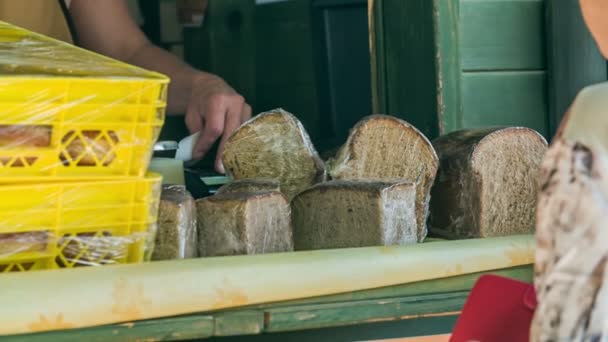 Молодая девушка, которая продает хлеб в пекарне дает чек пожилой женщине. - Кадры, видео