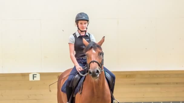 Un jinete joven está teniendo su sesión de equitación y sonríe de vez en cuando. Ella realmente disfruta montar a caballo. - Metraje, vídeo