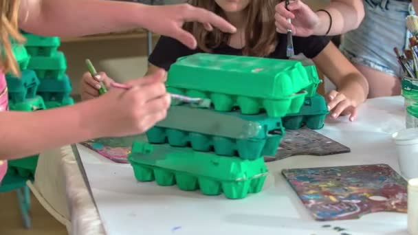 Muutama koululainen värittää munapakkauksia vihreiksi. heillä on hauskaa heidän taidekurssilla. - Materiaali, video