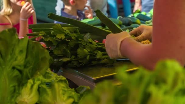 Ein Gemüsehändler wiegt Sellerie auf der Waage. Sie trägt auch Plastikhandschuhe. - Filmmaterial, Video