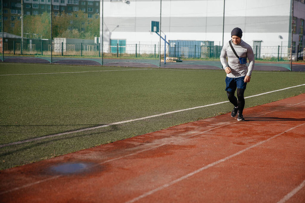 陸上競技場を走っている陸上競技の若者。健康的なライフスタイル - 写真・画像