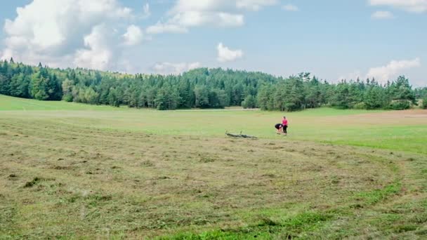 A couple is chilling in the middle of a big green meadow. They put their bicycles down on the ground next to a freshly cut gras. - Footage, Video