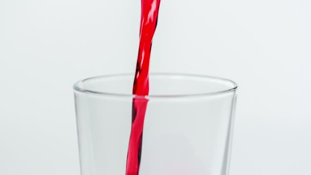 Valaki vörös folyadékot önt egy üres pohárba az asztalon.. - Felvétel, videó