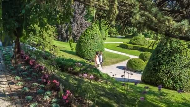 A young couple is walking on paths in a park during their photo shoot and a photographer is taking photos of them. - Footage, Video