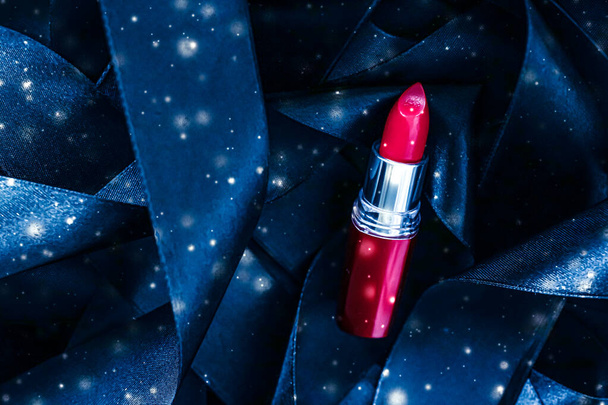 Lápiz labial rojo sobre seda azul y brillante fondo de brillo, maquillaje de lujo y cosméticos de belleza - Foto, Imagen