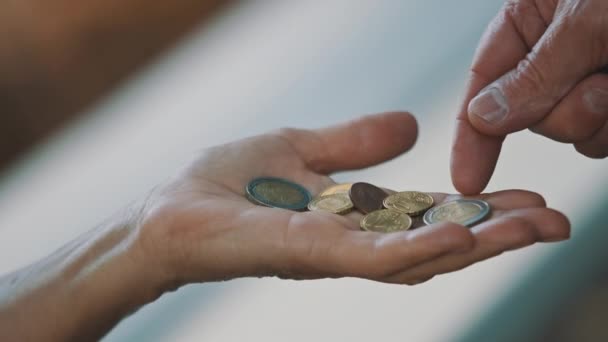 Close up, man hand giving coins to elderly homeless woman. Charity and support concept - Footage, Video
