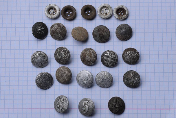 um jogo de botões militares cinzentos velhos encontra-se no papel branco - Foto, Imagem