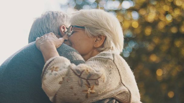 Coppia di anziani innamorati che si abbracciano nel parco in una giornata autunnale - Foto, immagini