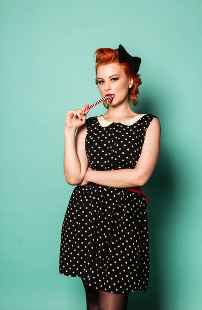 pin up girl with red hair in a polka dot dress with a Christmas candy stripe - Zdjęcie, obraz