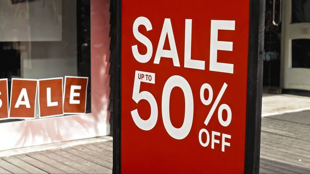 Red sign hanging on a glass window with the inscription sale up to 50% off - 写真・画像