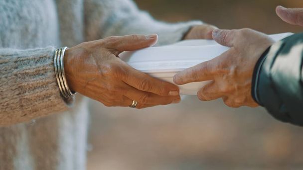 Женщина-волонтер помогает кормить бездомных бесплатной едой. Закрытие.  - Фото, изображение